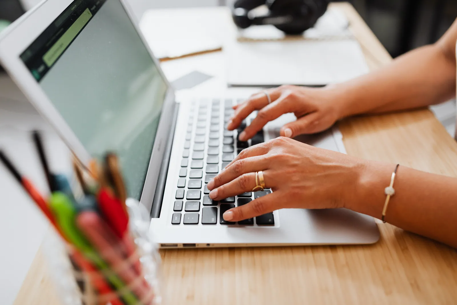 A person typing on a laptop at a wooden desk, showcasing a productive work environment