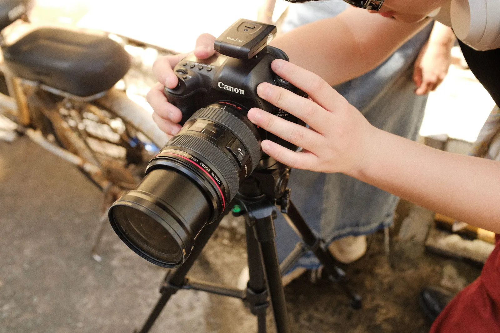 Photographer adjusting a DSLR camera on a tripod outdoors in a sunny setting