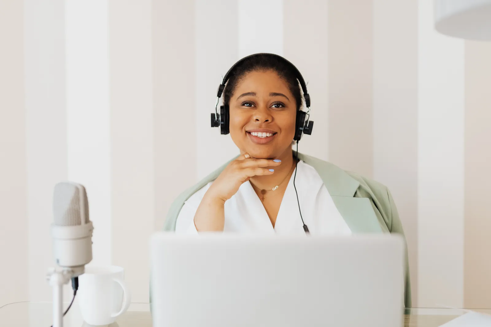 Smiling woman engaged in remote work with headphones and microphone setup