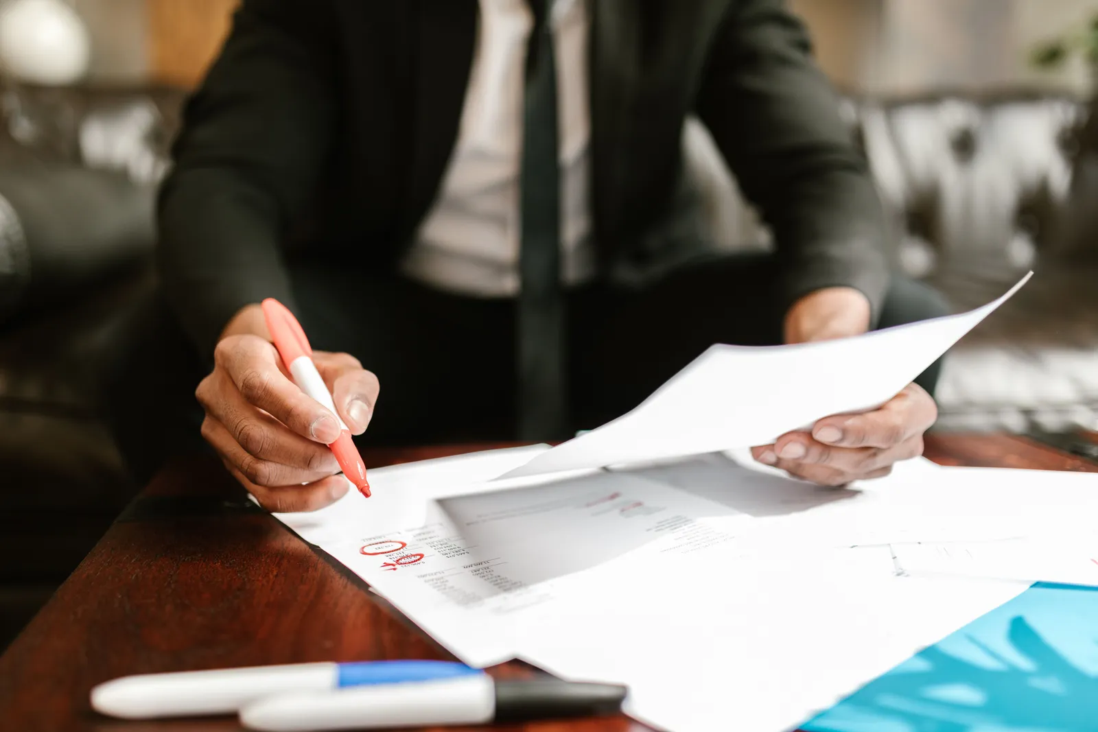 Businessman working with financial documents at office desk, highlighting details