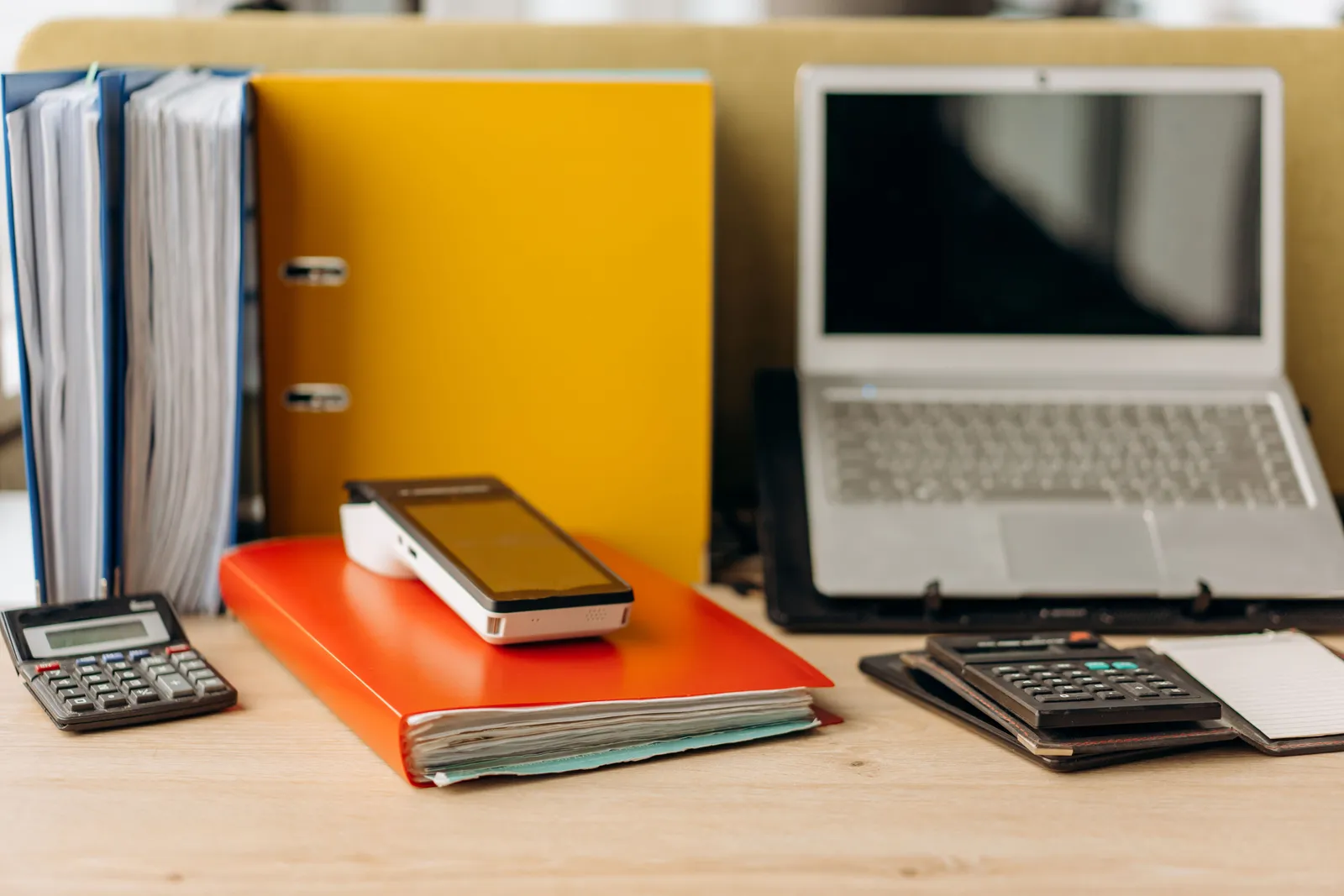 Office desk setup with laptop, documents, and calculators, ideal for business productivity