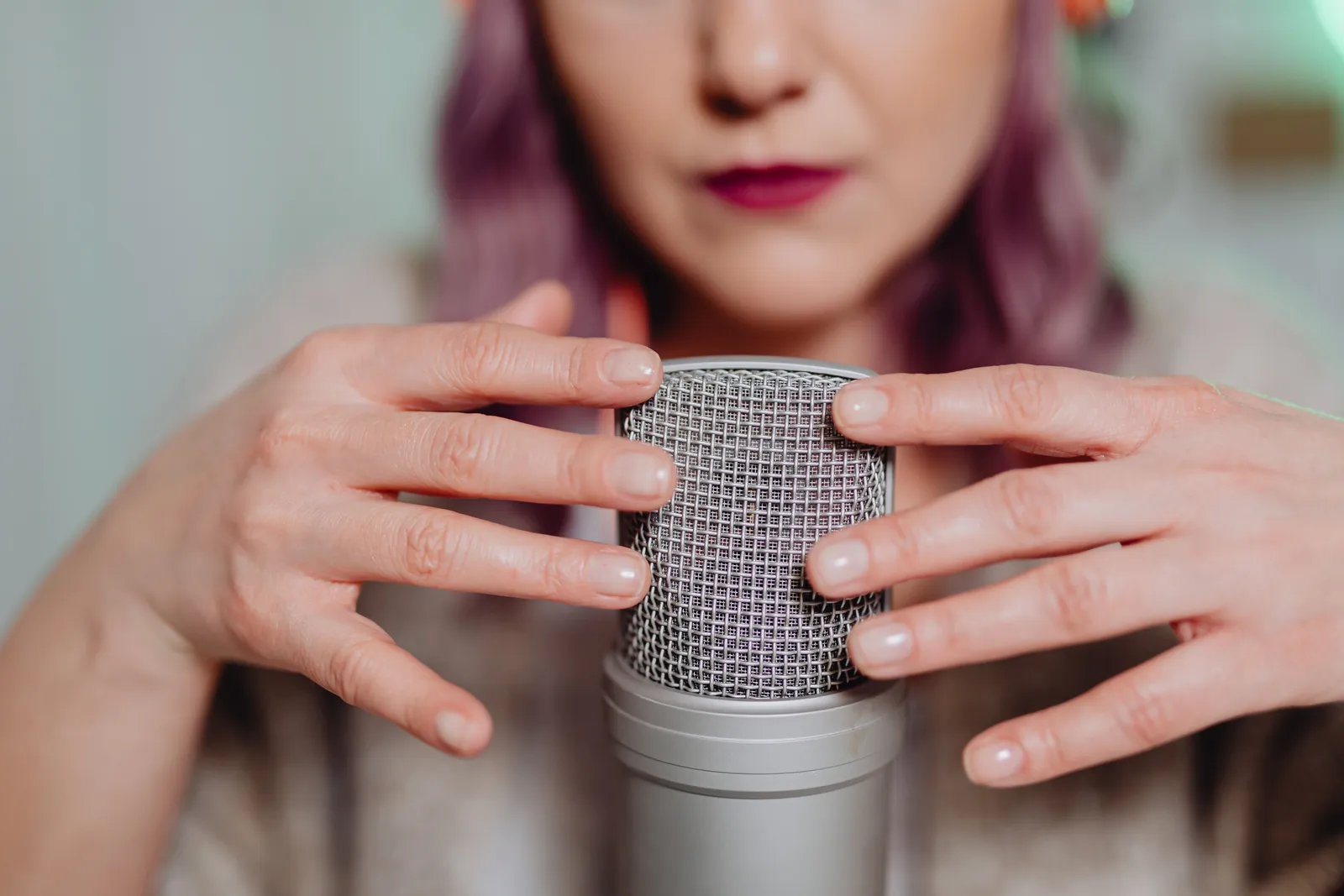 Woman using a microphone for ASMR recording indoors, creating soothing audio