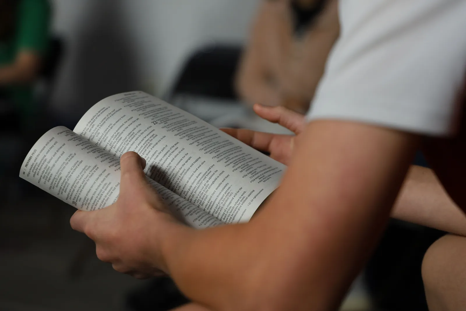 Focused shot of hands holding an open book indoors, promoting reading and education