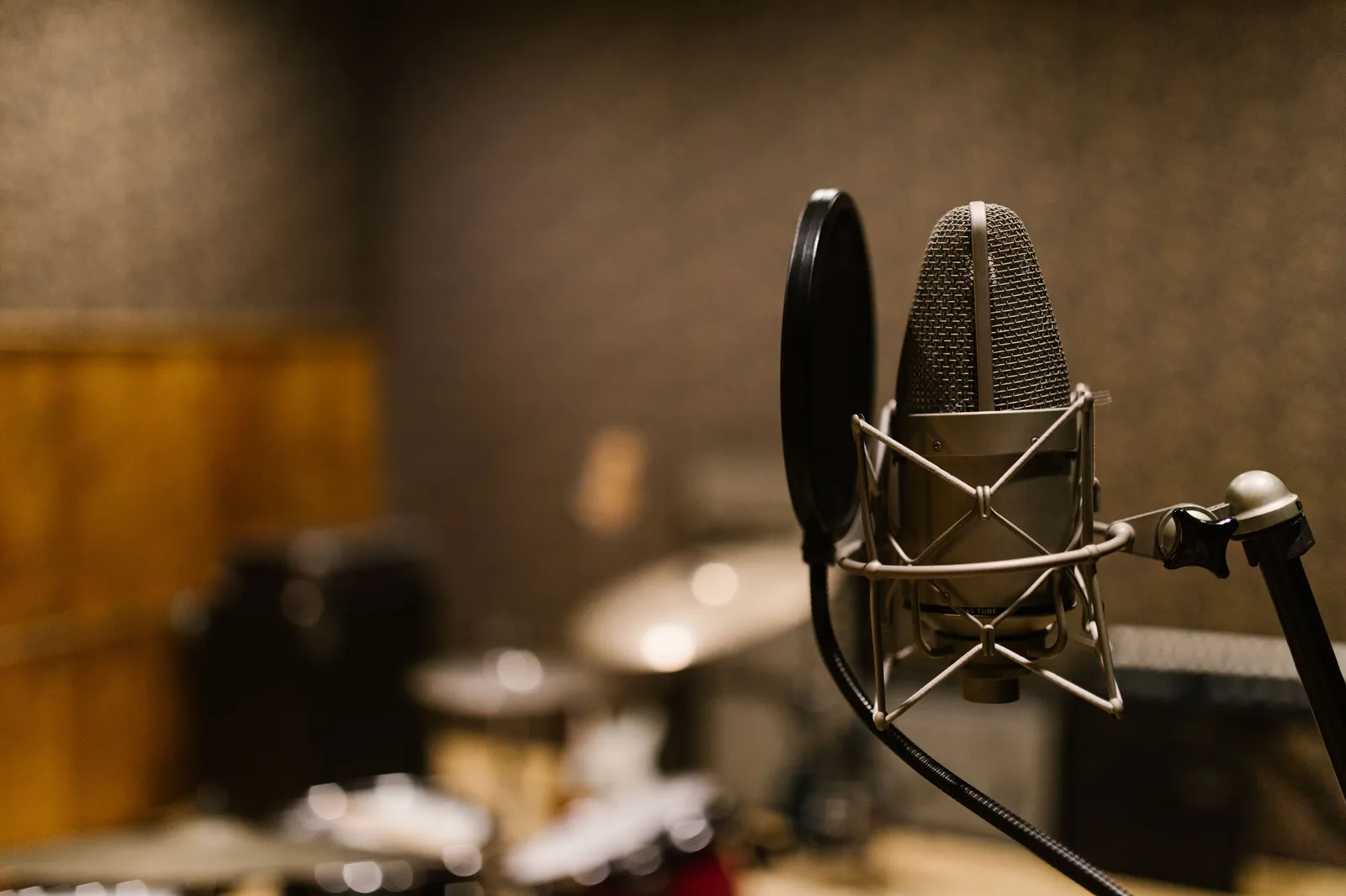 Close-up of a condenser microphone with a pop filter in a recording studio setting