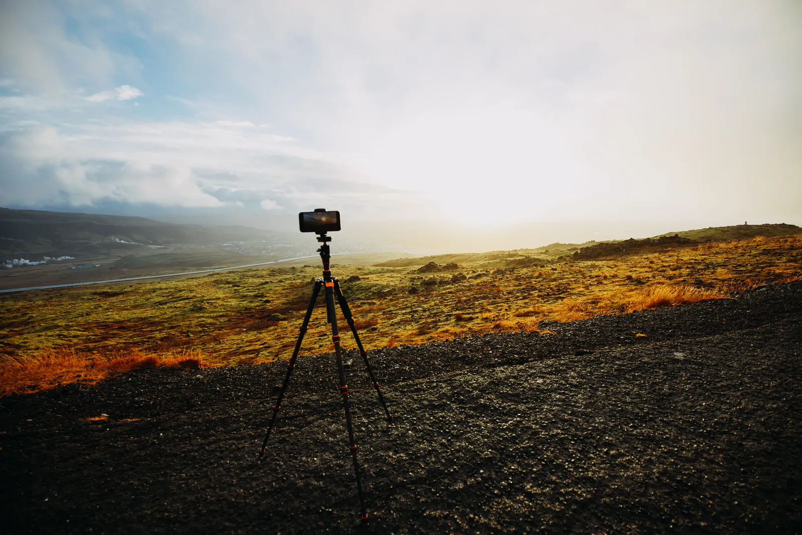 A serene countryside view with a camera on tripod capturing the scenic landscape at sunrise