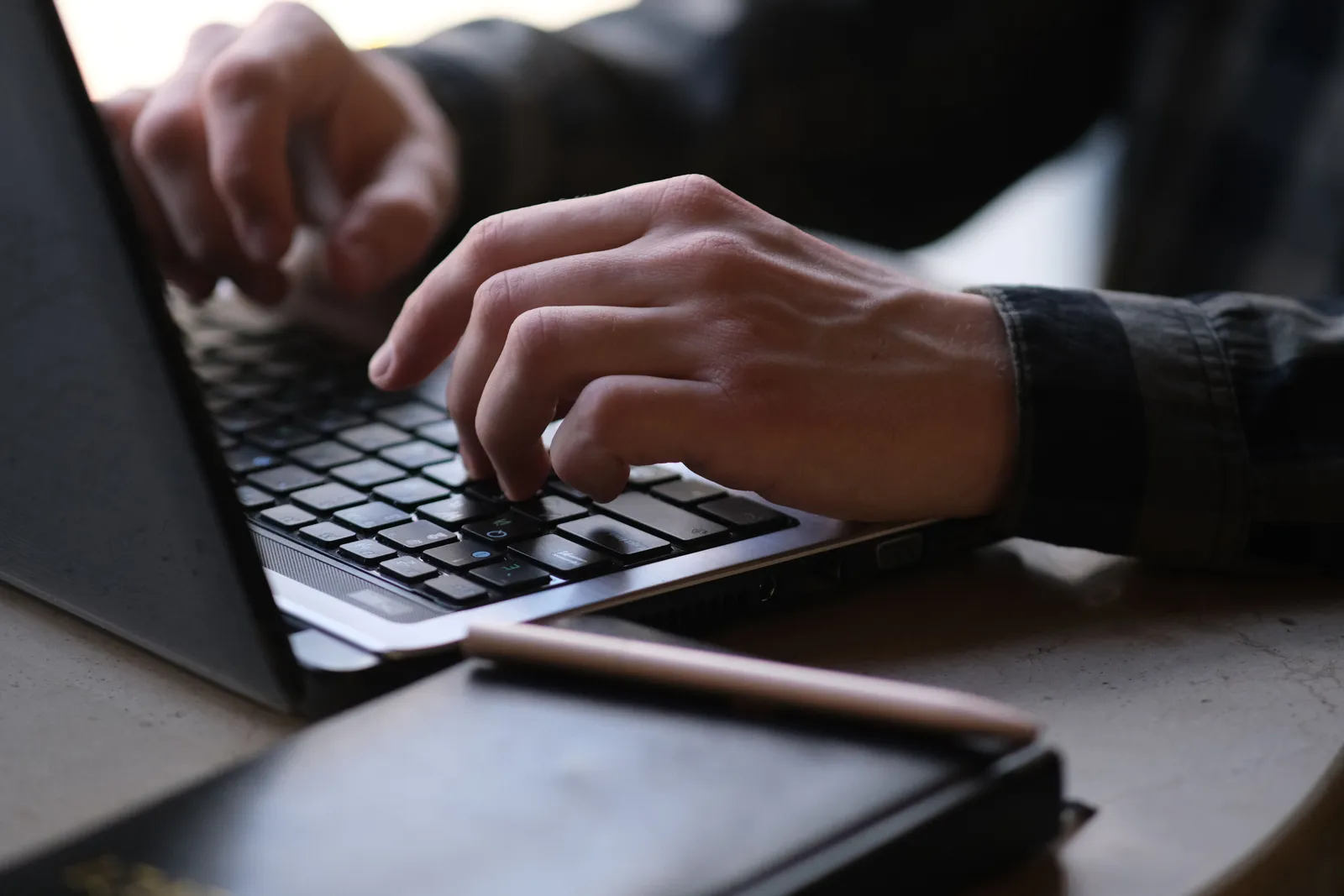 Close-up photo of hands typing on a laptop, perfect for remote work or digital nomad themes