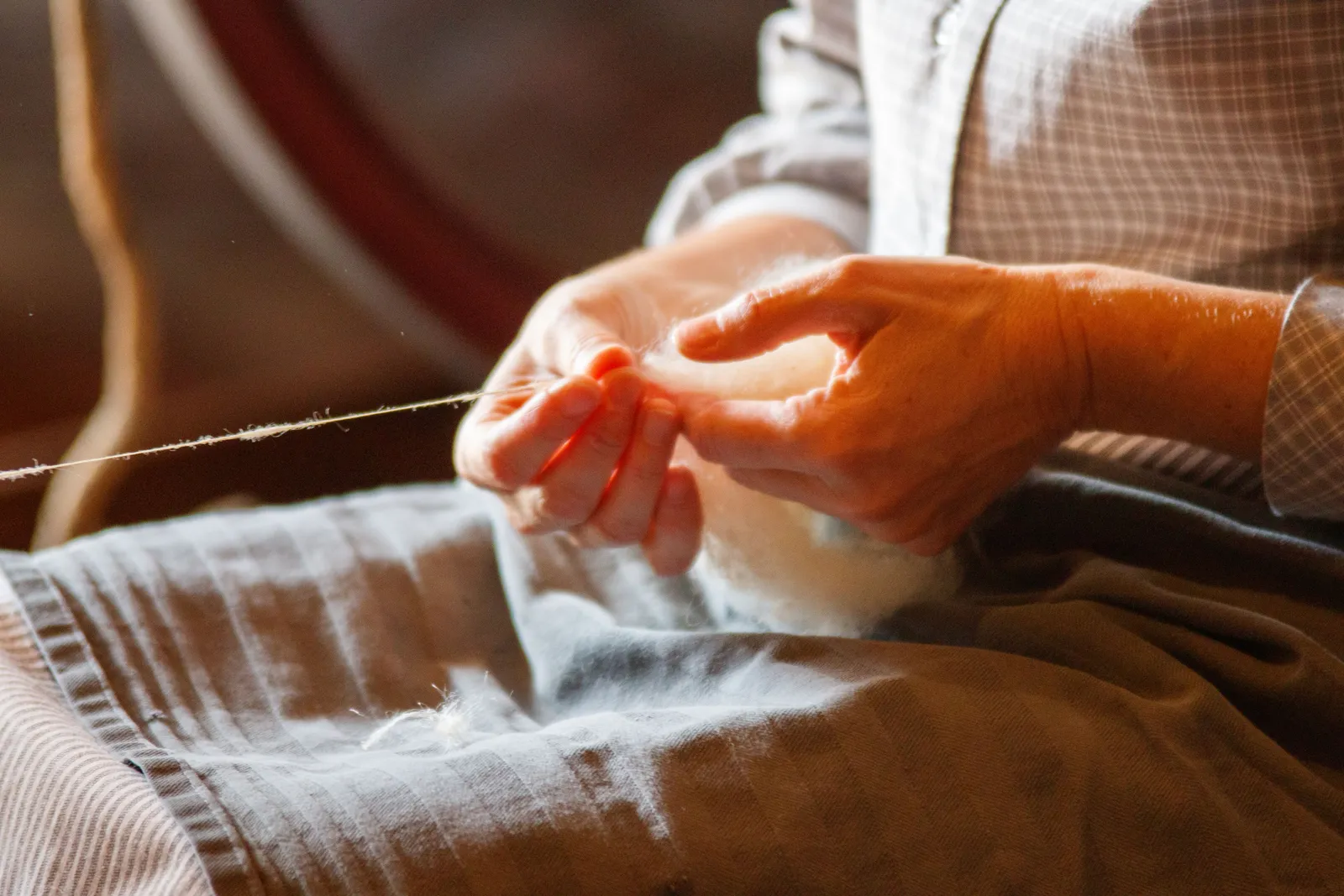 A person's hands skillfully spinning wool into yarn using traditional methods