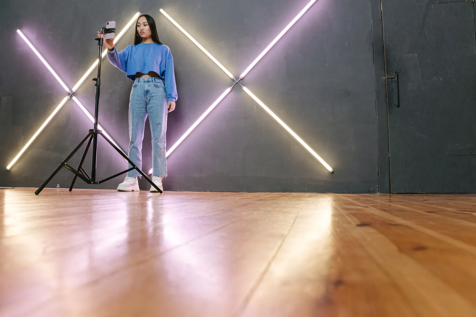 Teenager recording content with a smartphone on tripod in a modern studio with LED lights