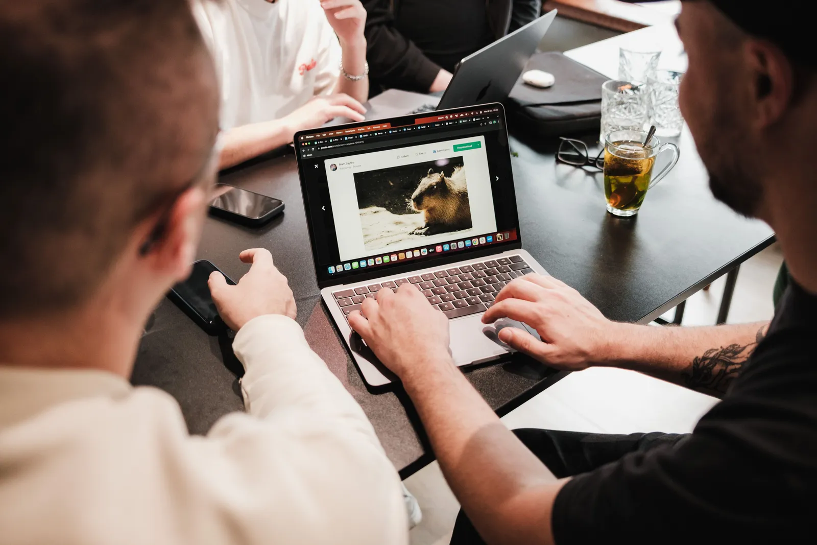 A group of men collaborating at a desk with laptops, showcasing teamwork and technology use in an office environment
