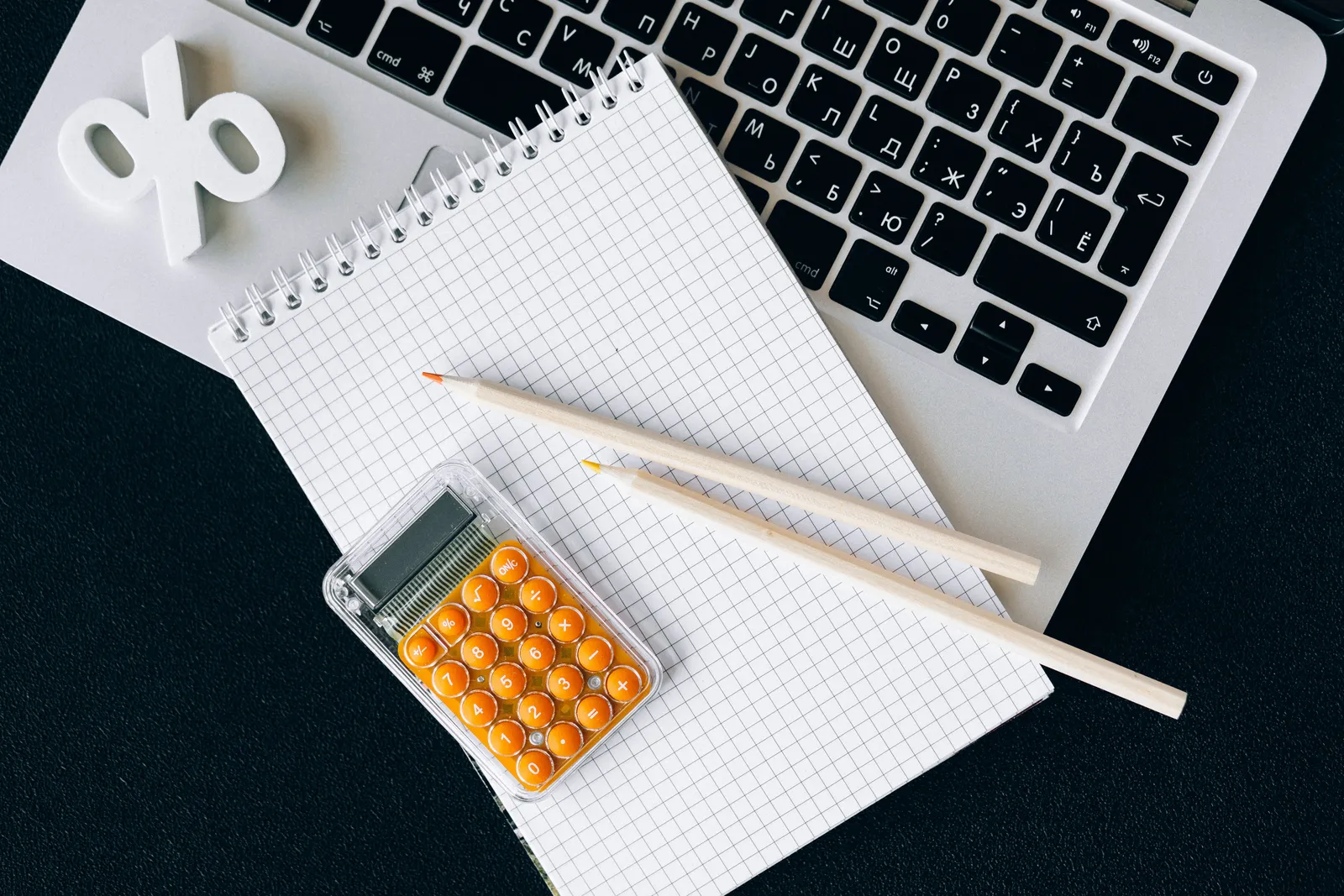 Flat lay of office supplies including a calculator and notebook on a laptop desk