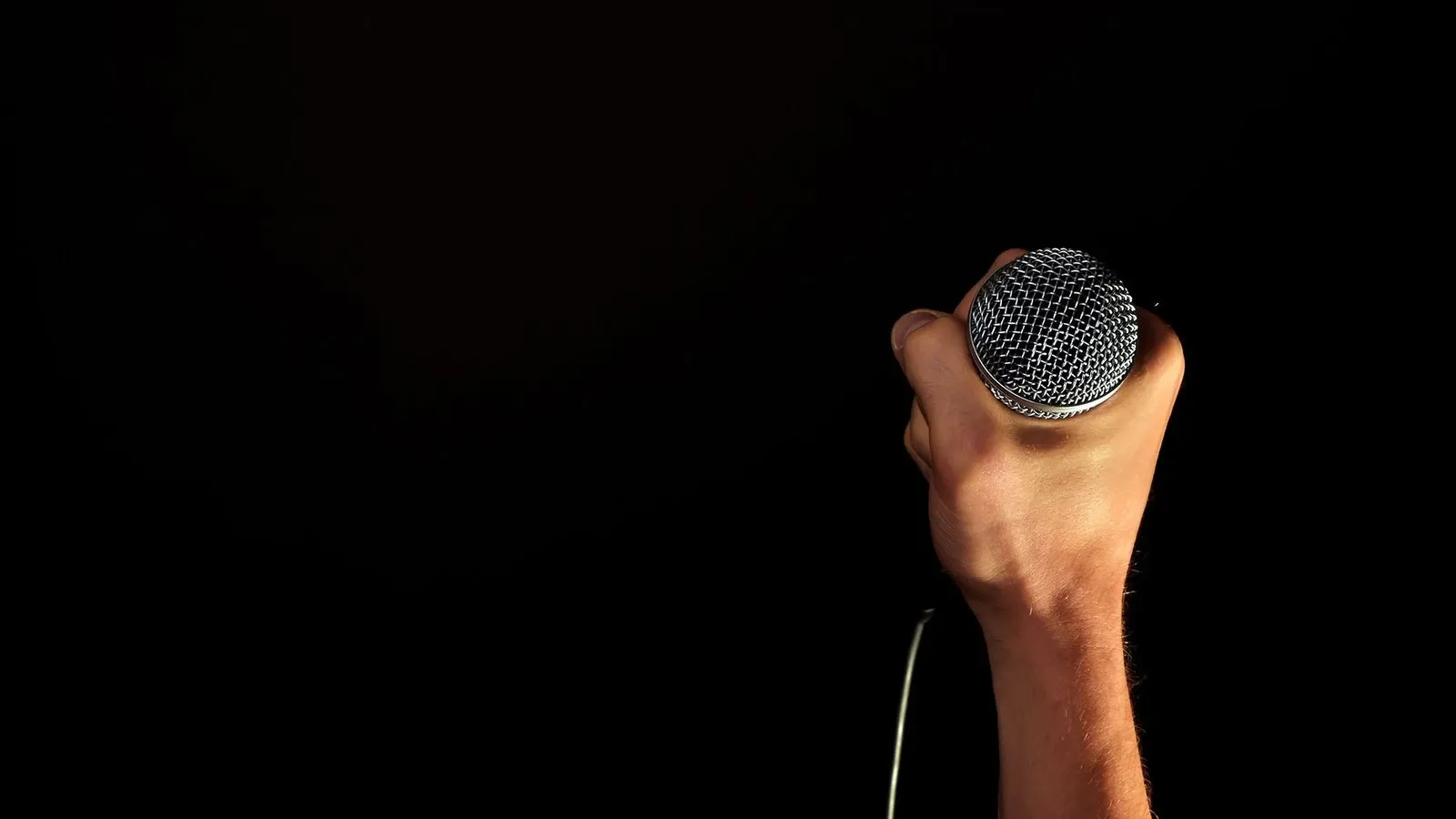 A hand holding a microphone ready to record speech