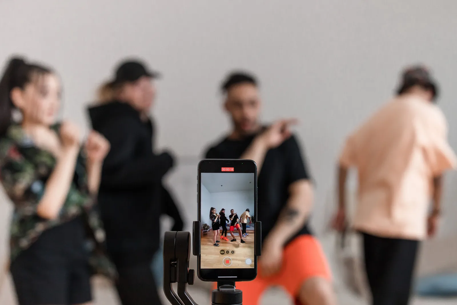 Group of dancers recording performance with smartphone on tripod, capturing trendy dance moves