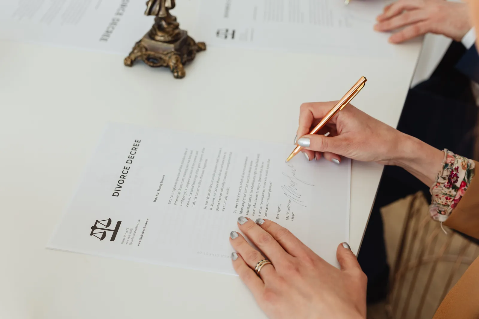 Close-up of hands signing a divorce decree document on a desk, showcasing legal process