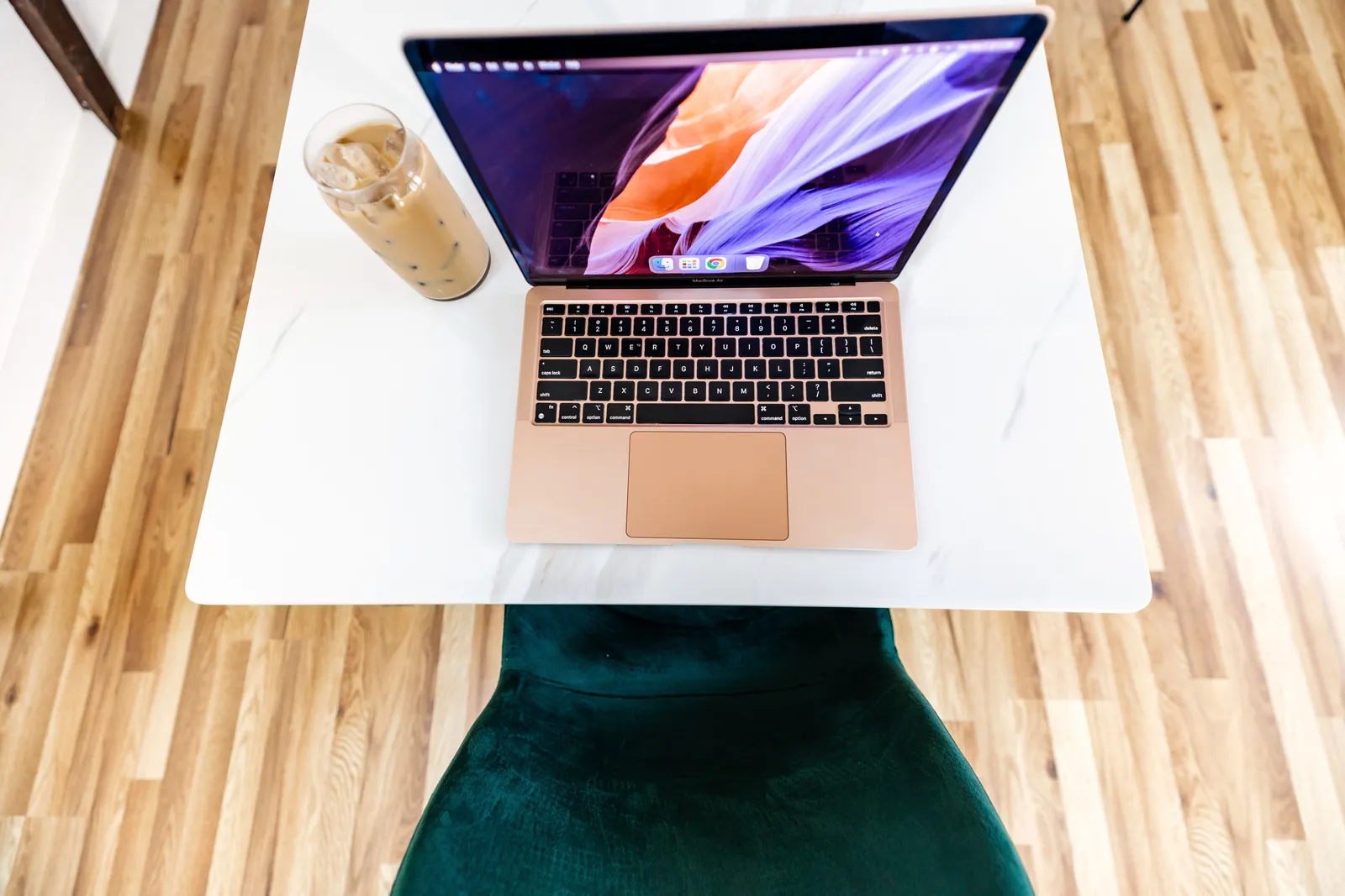 Top view of a stylish workspace featuring a laptop and iced coffee on a marble desk