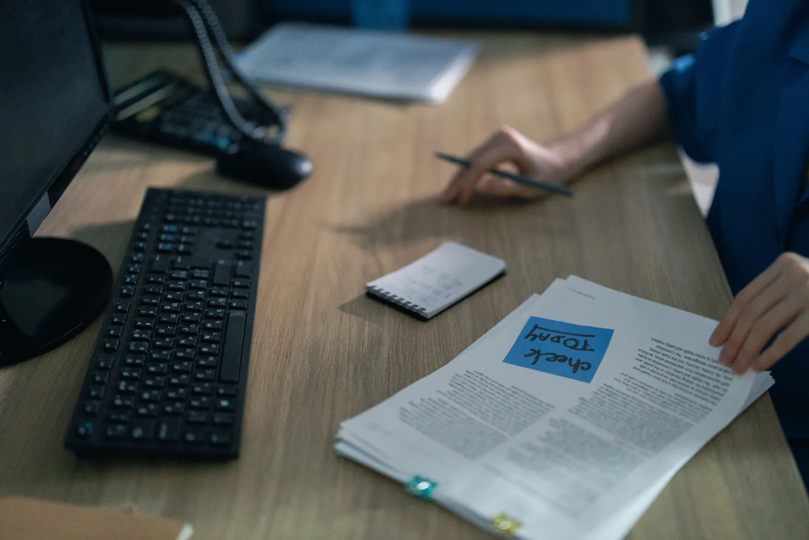A close-up of a computer keyboard and documents on a desk in an office setting, highlighting workplace organization