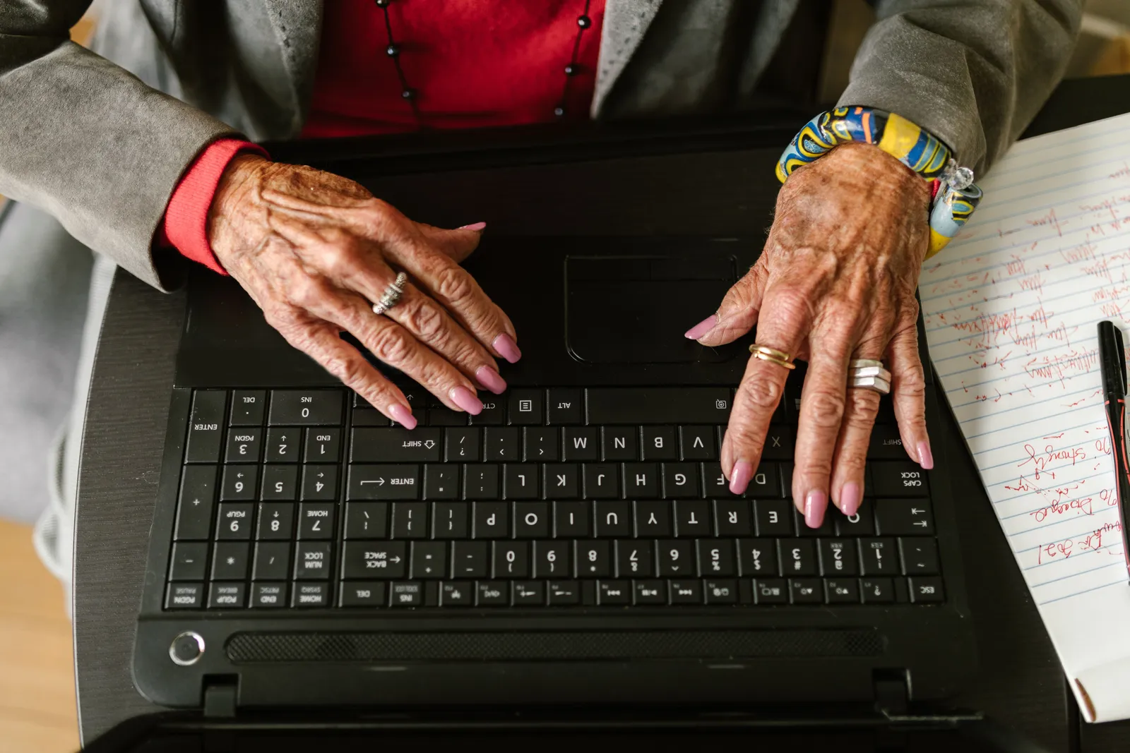 Close-up of senior woman's hands typing on laptop with rings and manicured nails