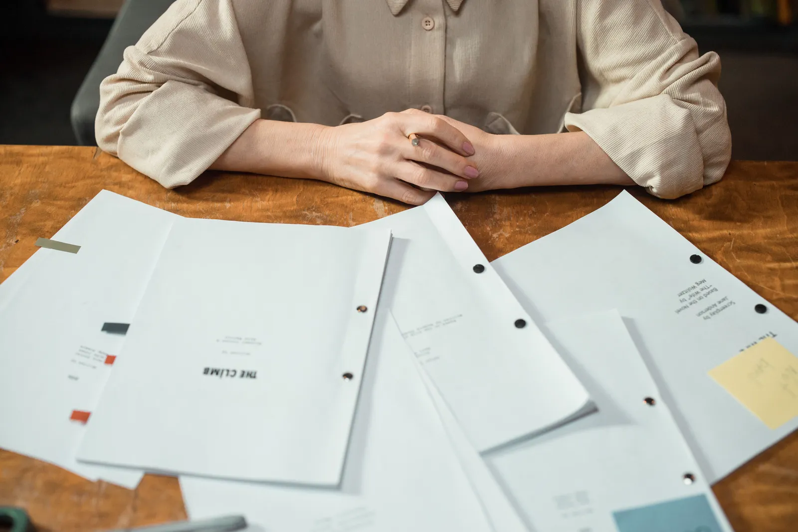 Close-up of a woman's hands with business documents on a wooden desk in an office setting