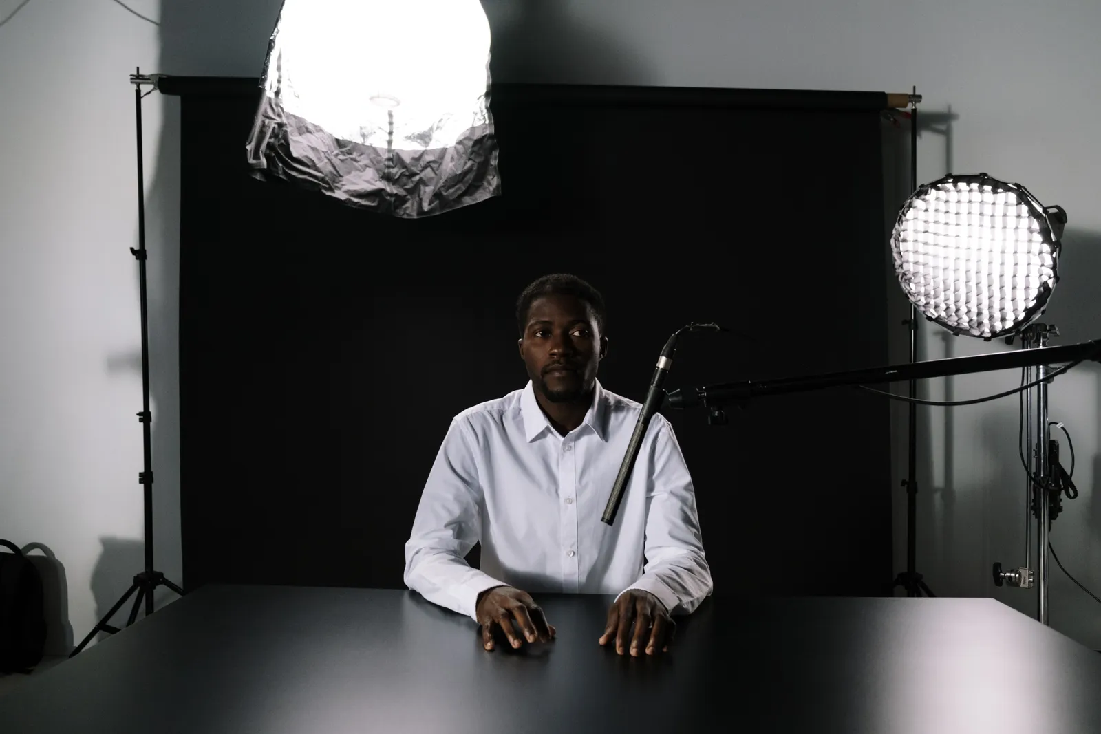 Man in a podcast studio sitting at a table with microphone and lighting equipment