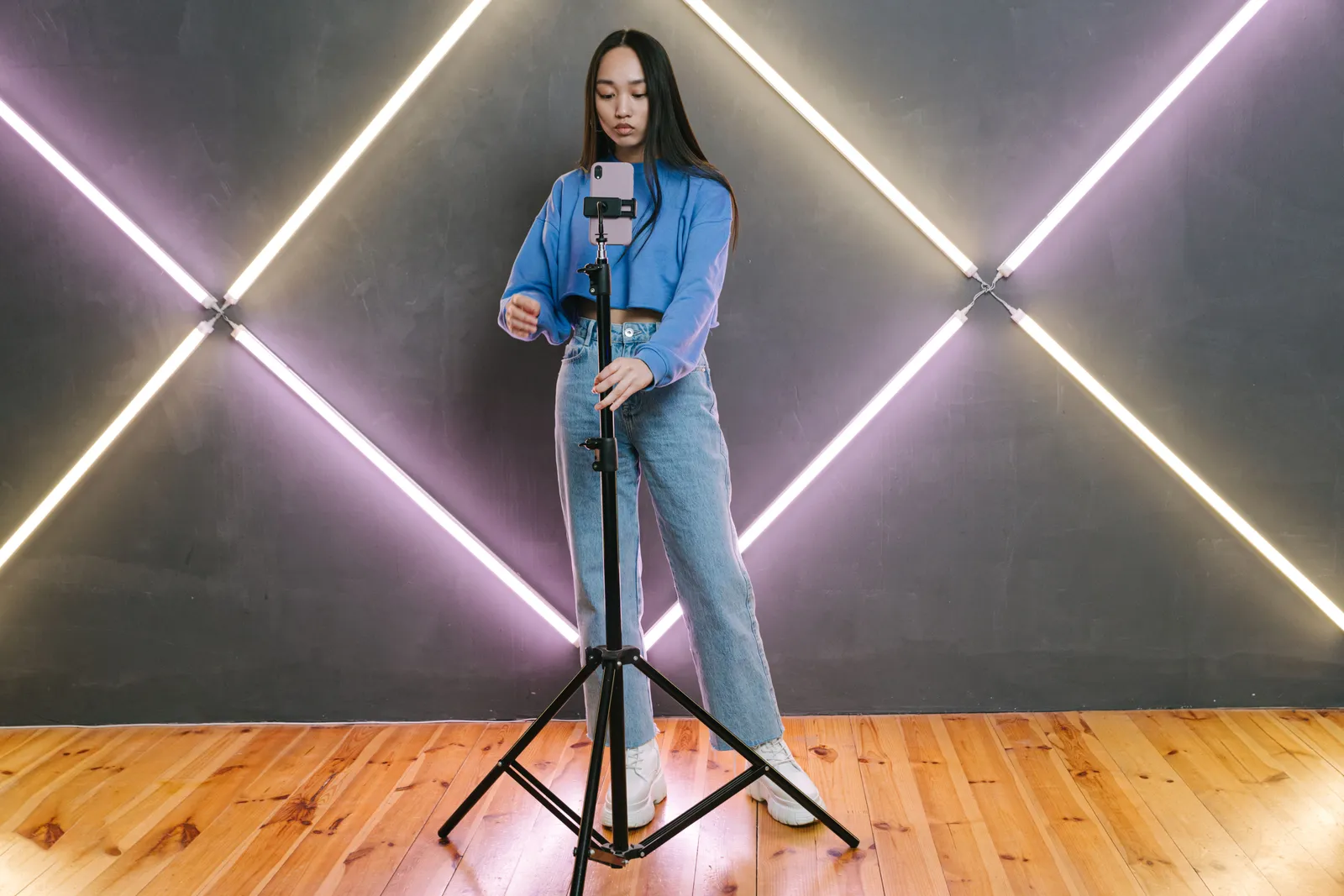 Woman preparing for a livestream with smart phone on tripod indoors
