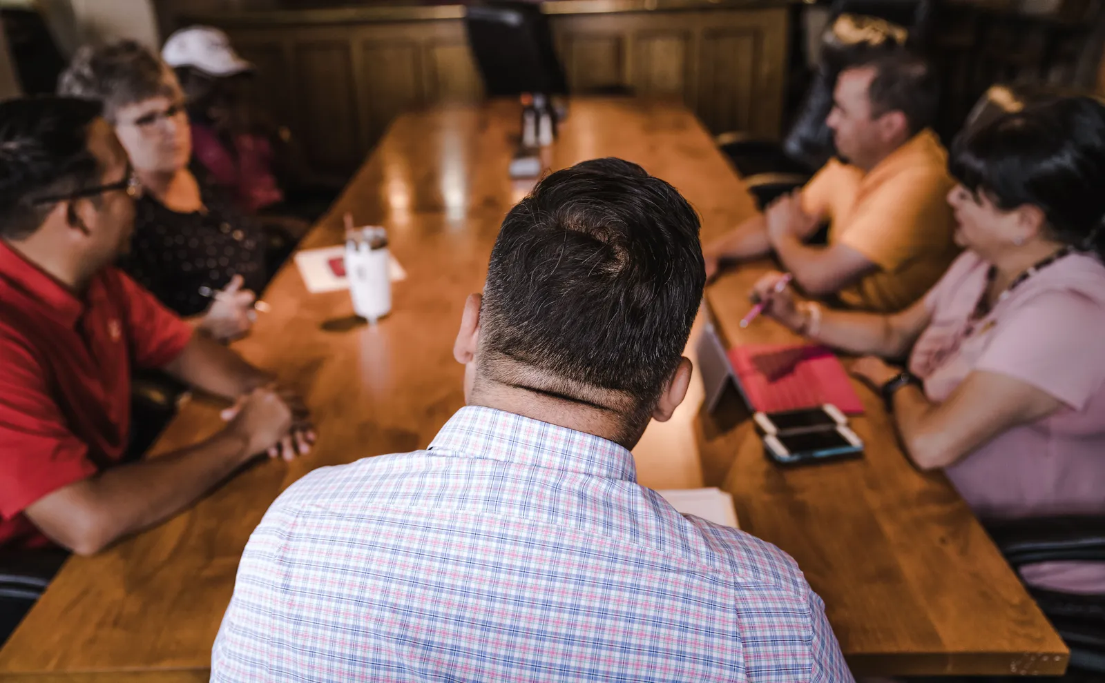 A business meeting with a diverse team discussing around a wooden table in an office setting