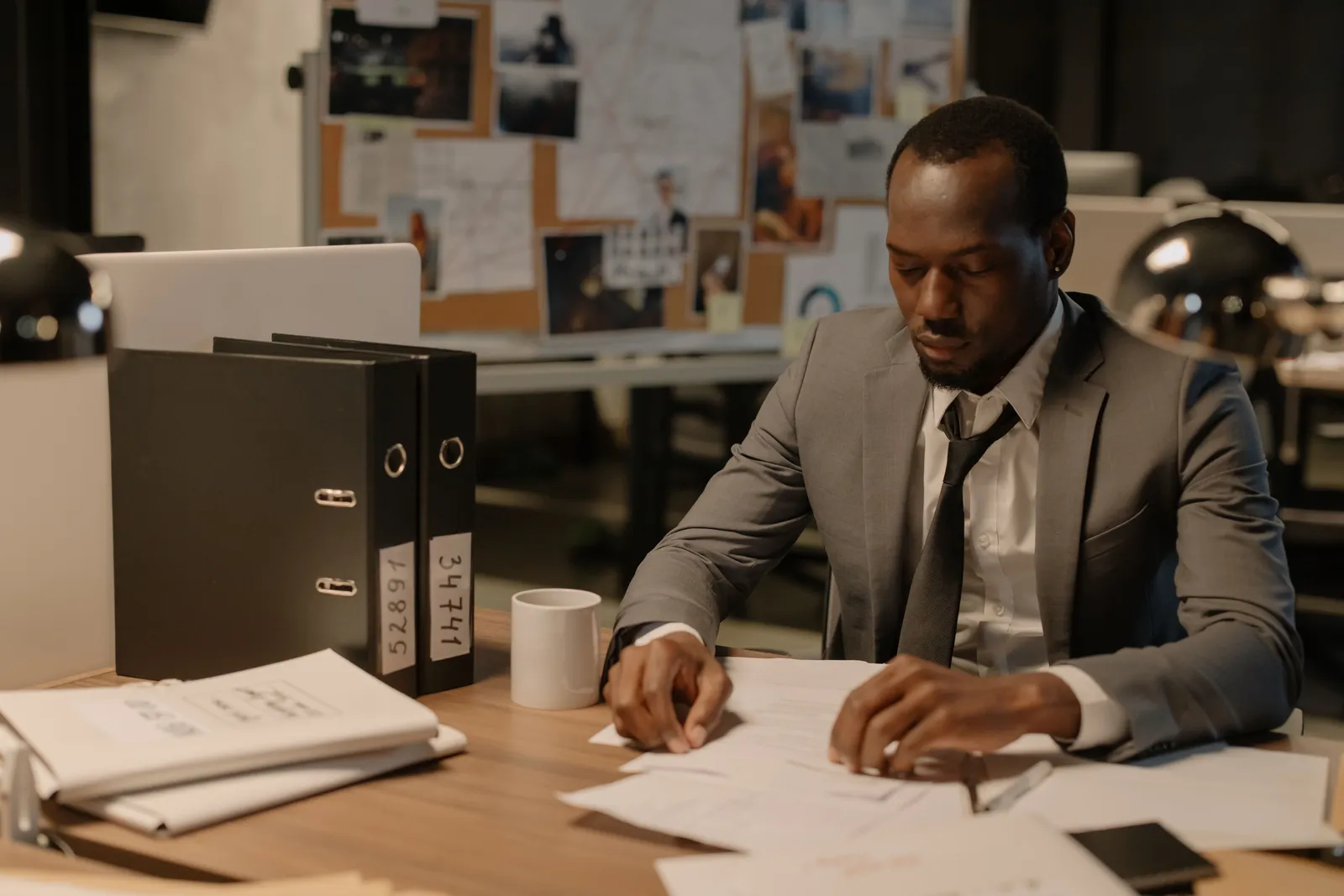 Man in business suit working late at office desk with documents and files