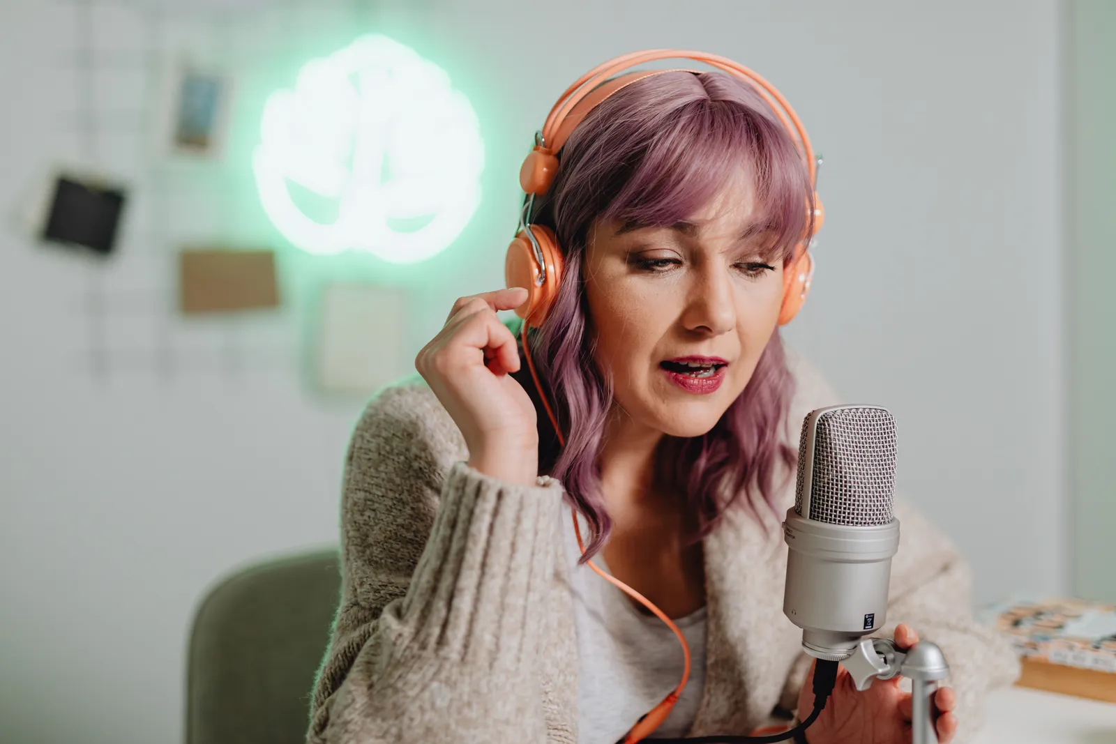 A woman recording a podcast indoors with headphones and a microphone