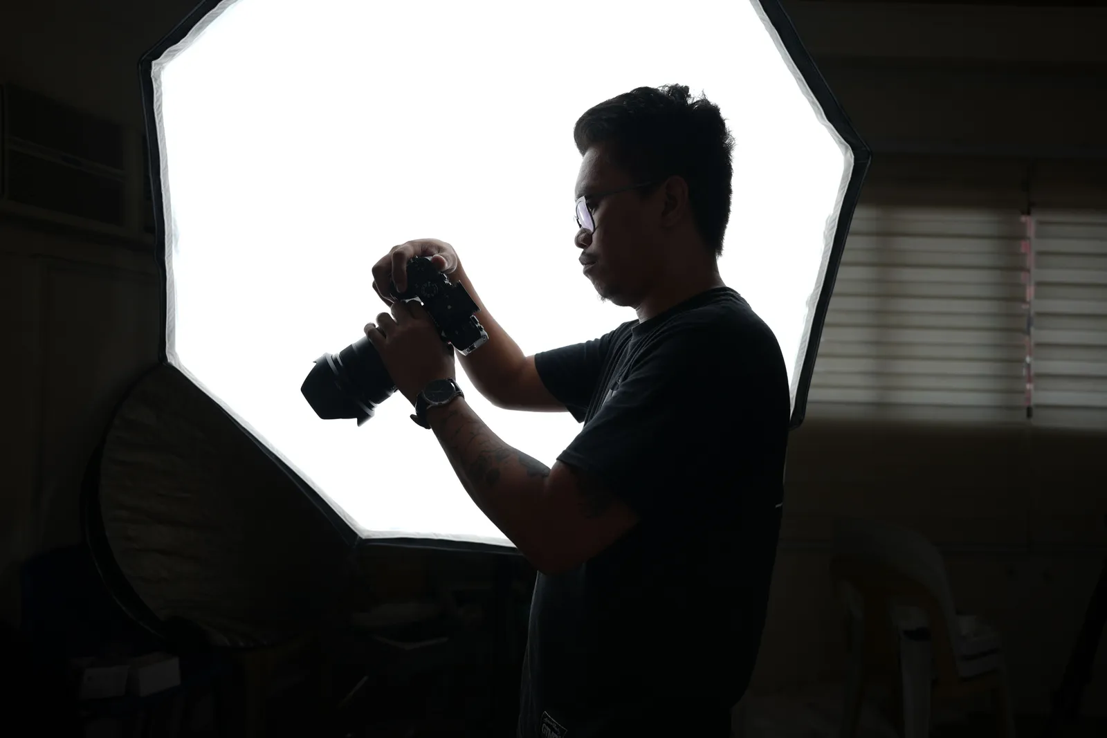 A professional photographer adjusting camera equipment in a studio setting with softbox lighting