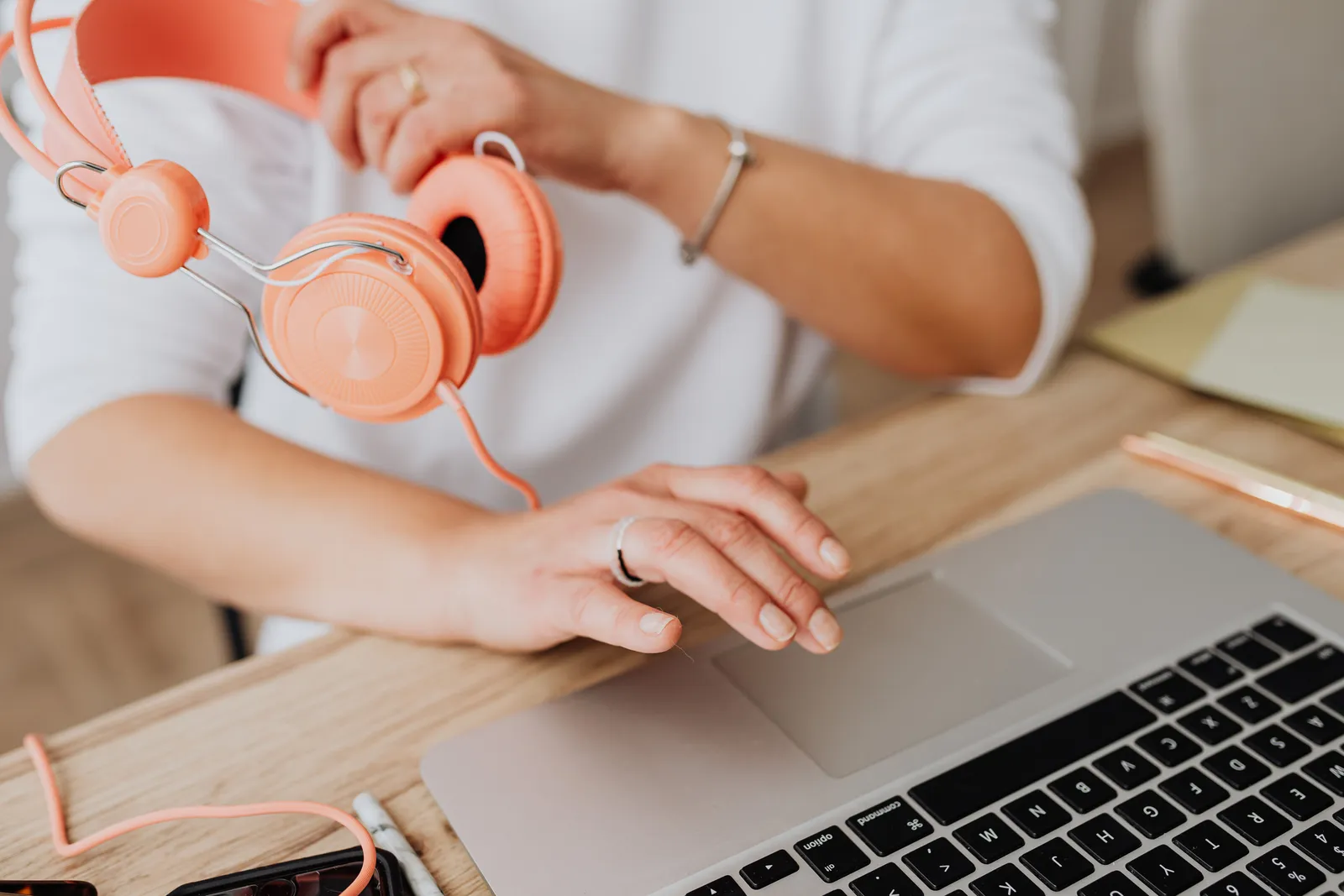 Person holding headphones while using laptop, close-up view