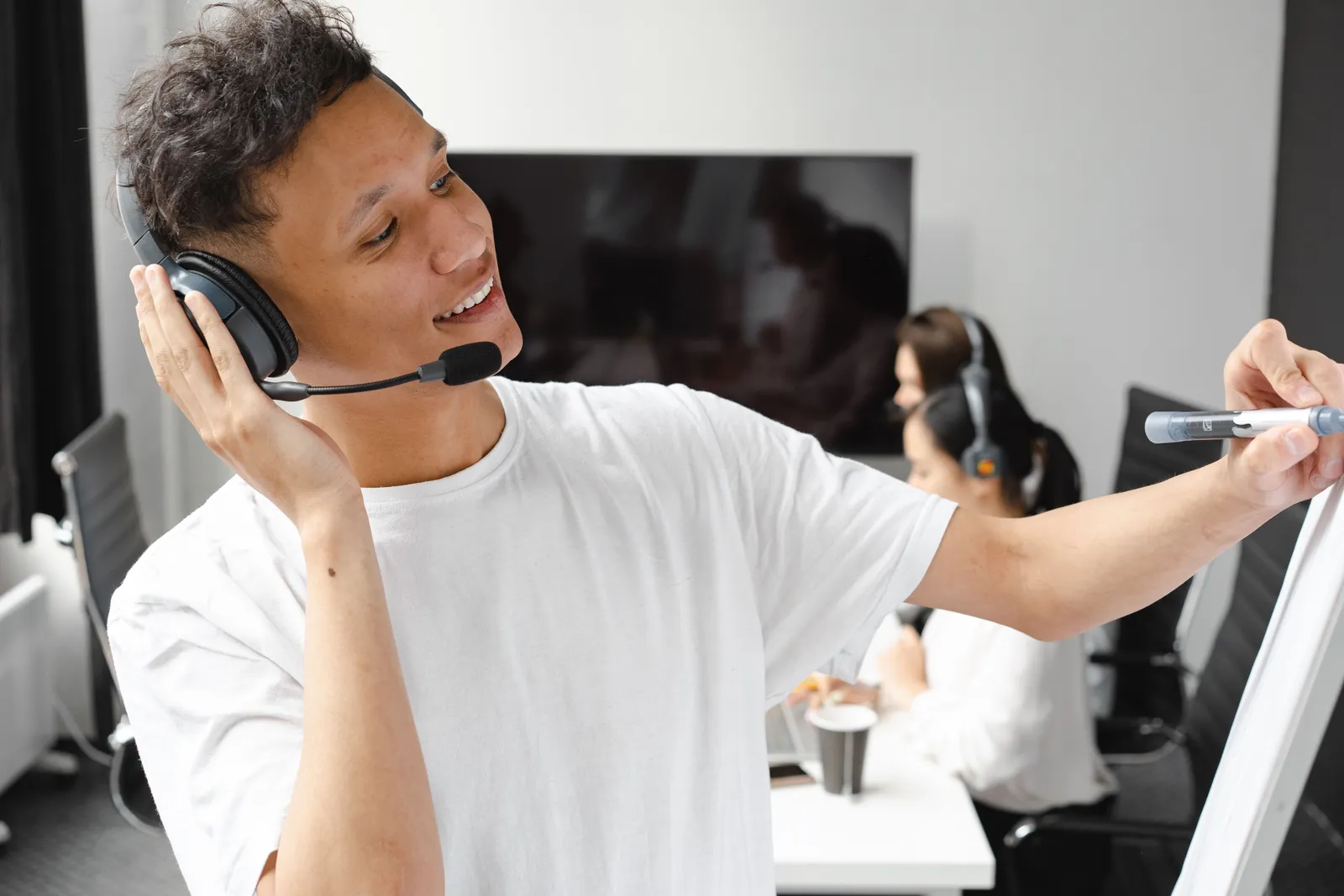 Man in office using headset and whiteboard for online teaching session