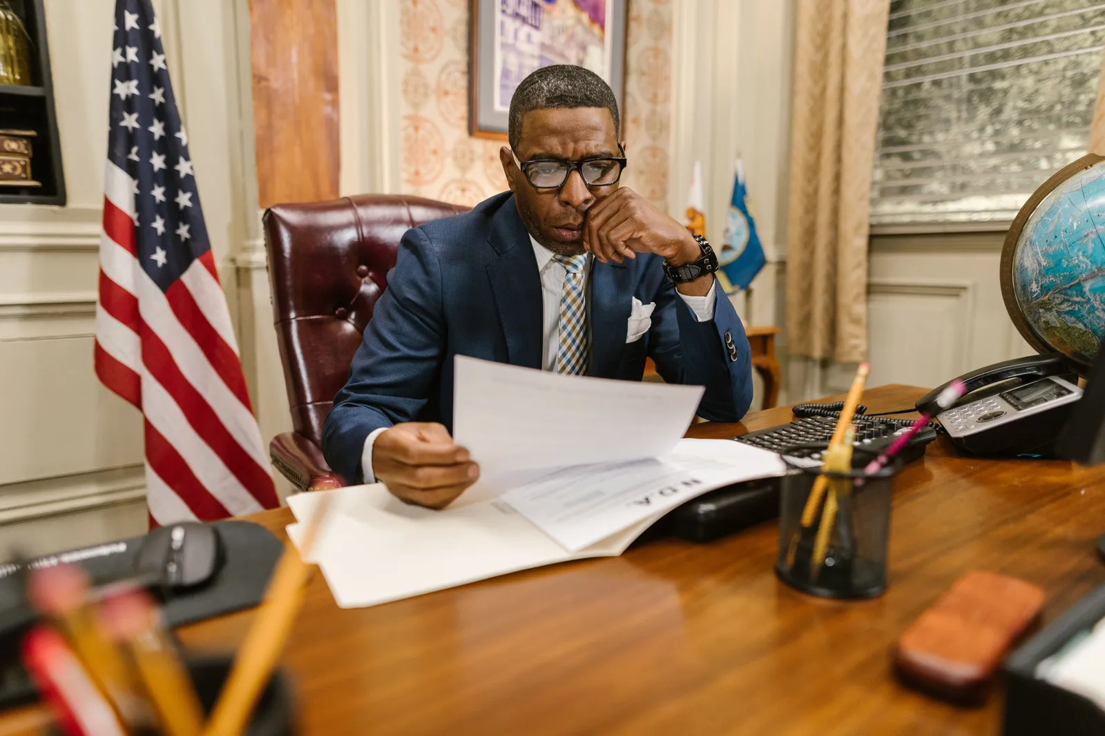 A lawyer in a suit deeply engaged in reviewing legal documents at his office desk