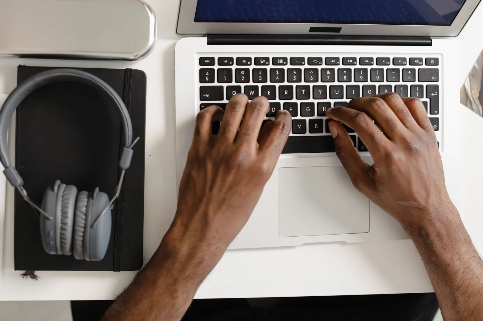 Overhead view of hands typing on a laptop keyboard with headphones nearby