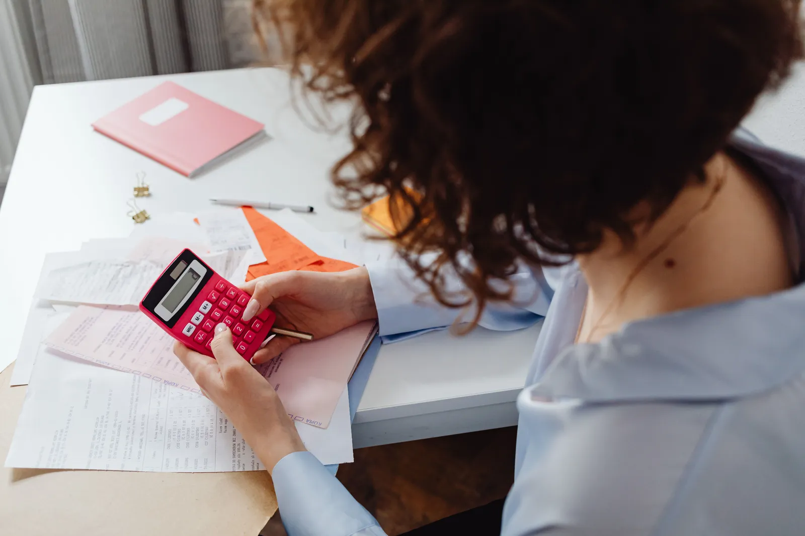 Woman calculating expenses with documents and calculator at work desk