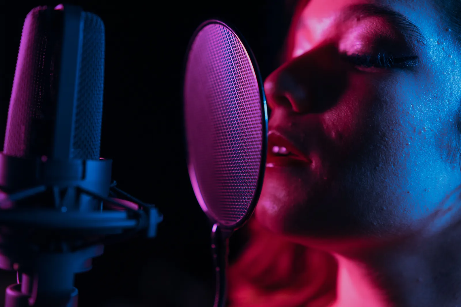 A dynamic shot of a woman singing into a microphone with vibrant lighting