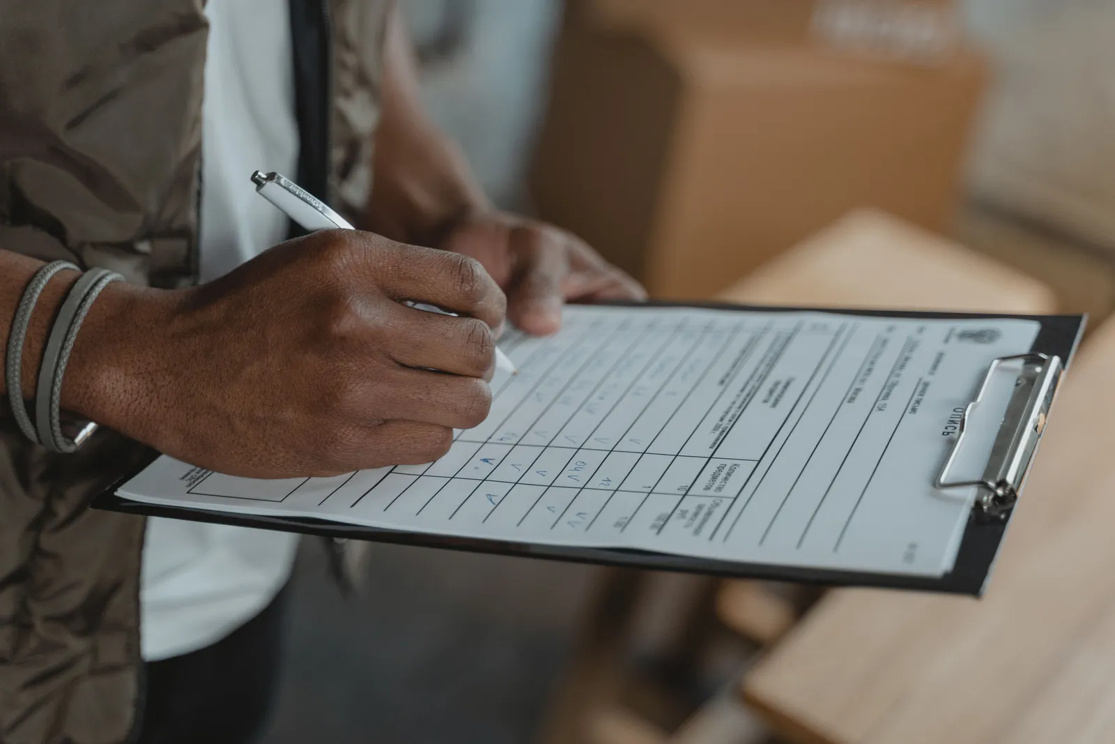 Close-up of person writing on form attached to clipboard, capturing the diligent process