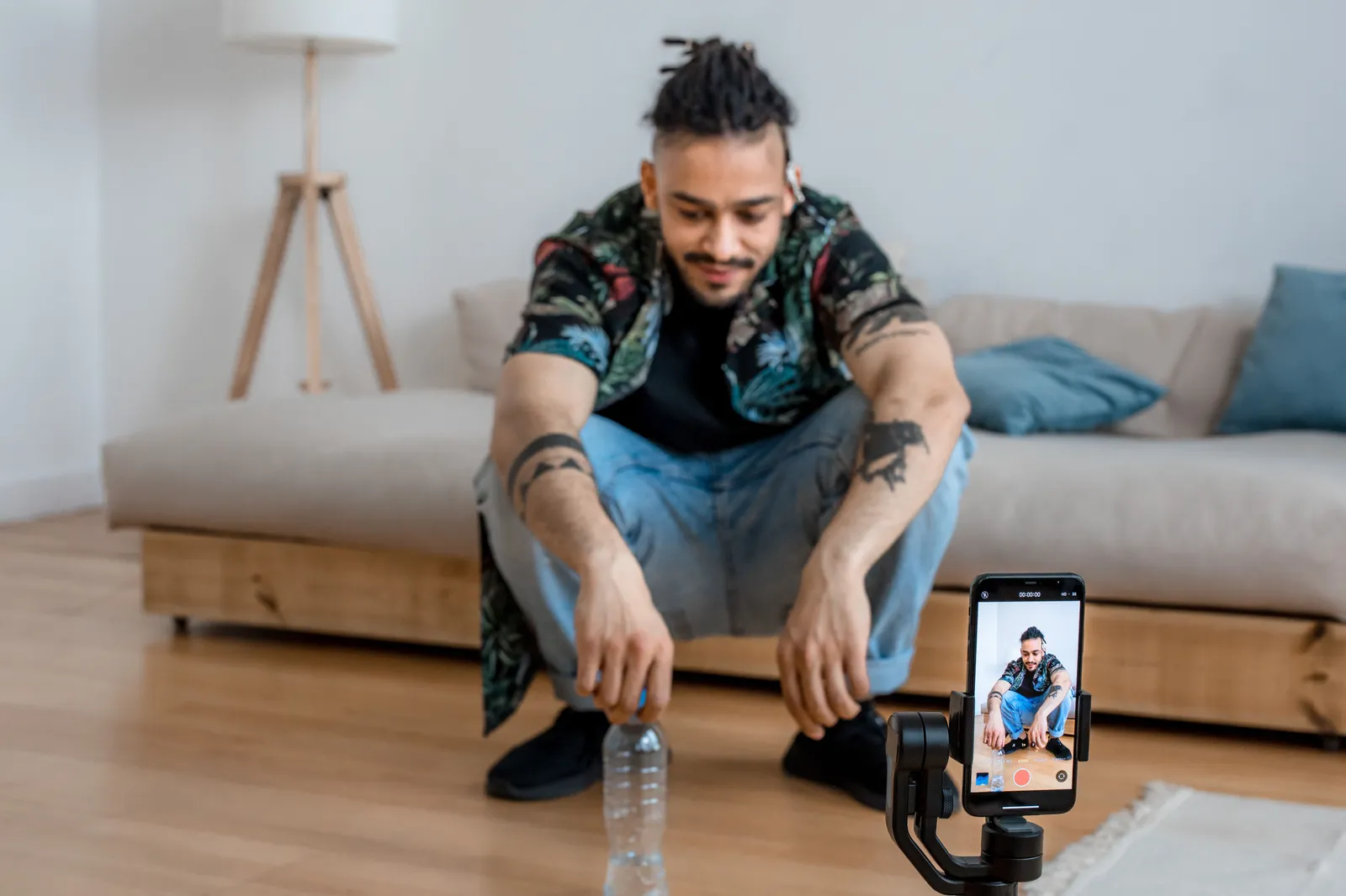 Young man recording content in living room with smartphone on a tripod