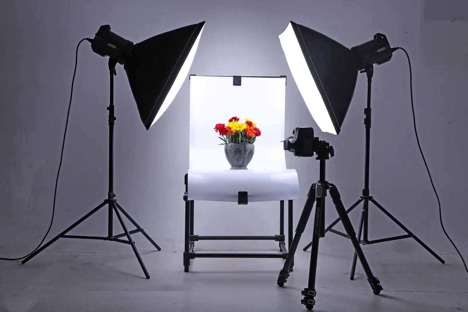 Studio setup with lights and camera capturing flowers in a vase, ideal for product photography