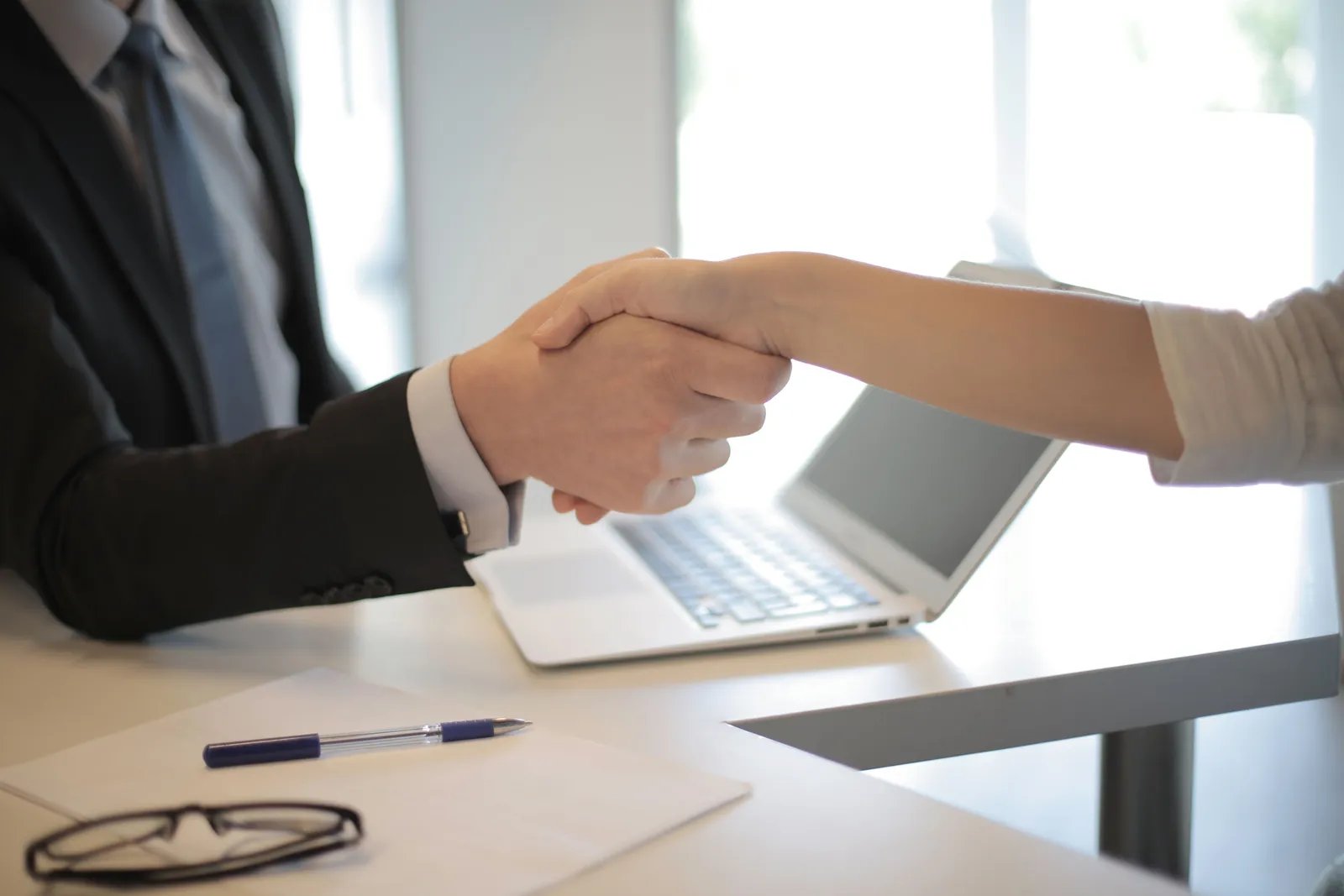 Close-up of a professional handshake over a laptop during a business meeting in an office