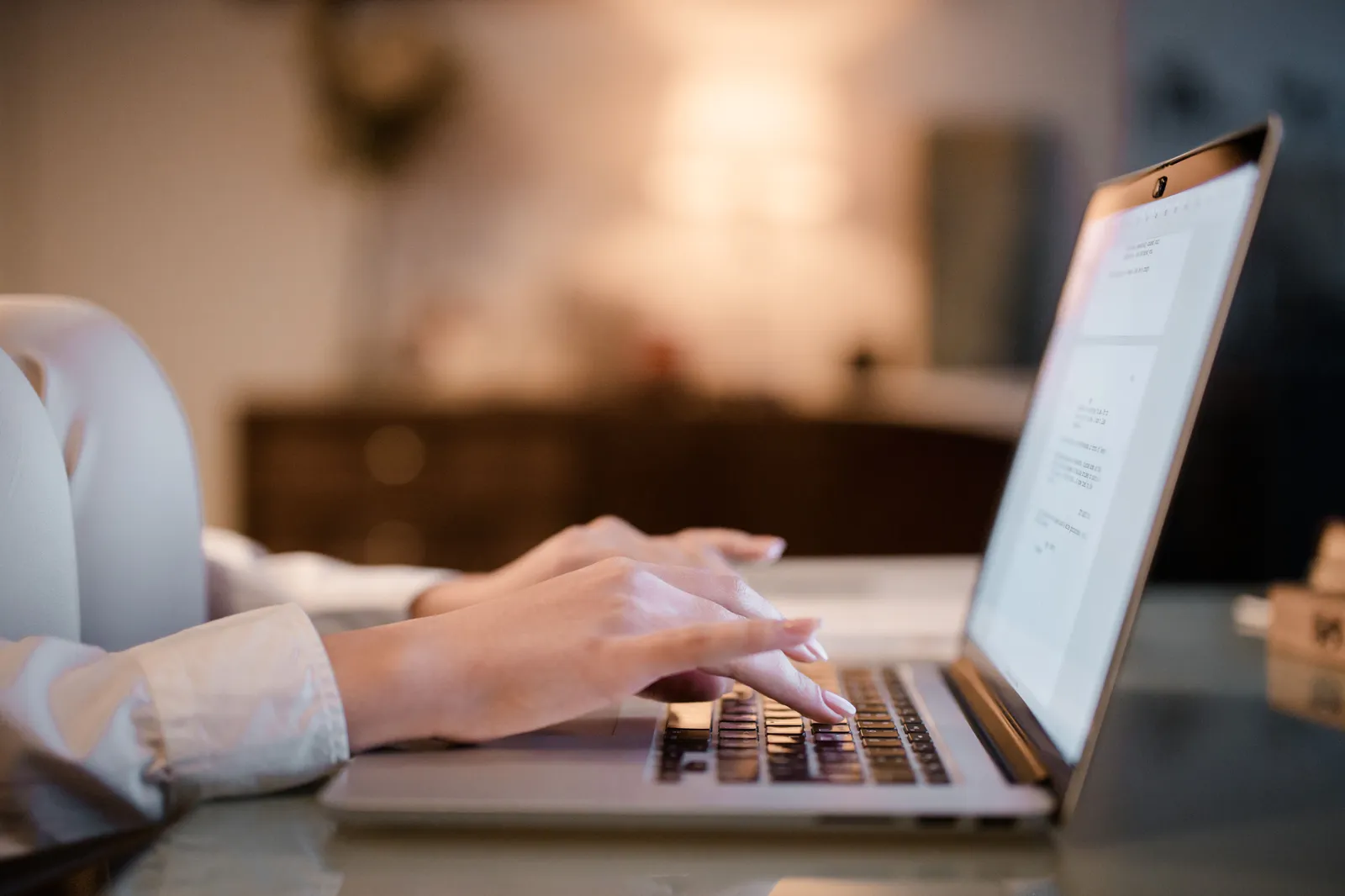 Close-up of hands typing on a laptop at home, showcasing a cozy work environment