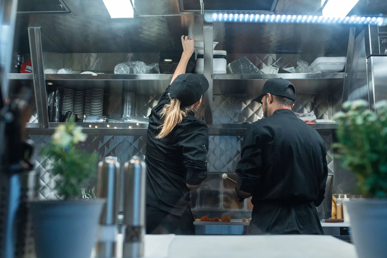 Two chefs working together in a commercial kitchen, preparing food