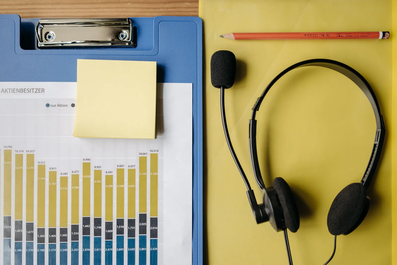 Flat lay of office items including a graph, headset, and stationery on a desk
