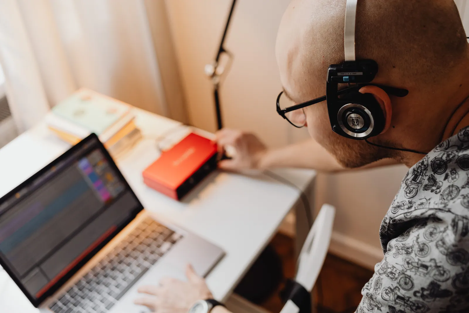 A bald man with headphones working on audio equipment in a modern workspace