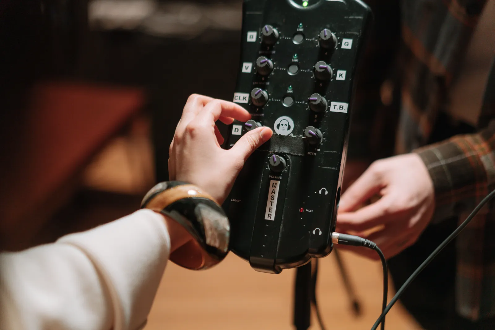 Close-up of hands adjusting audio device controls for music production and recording